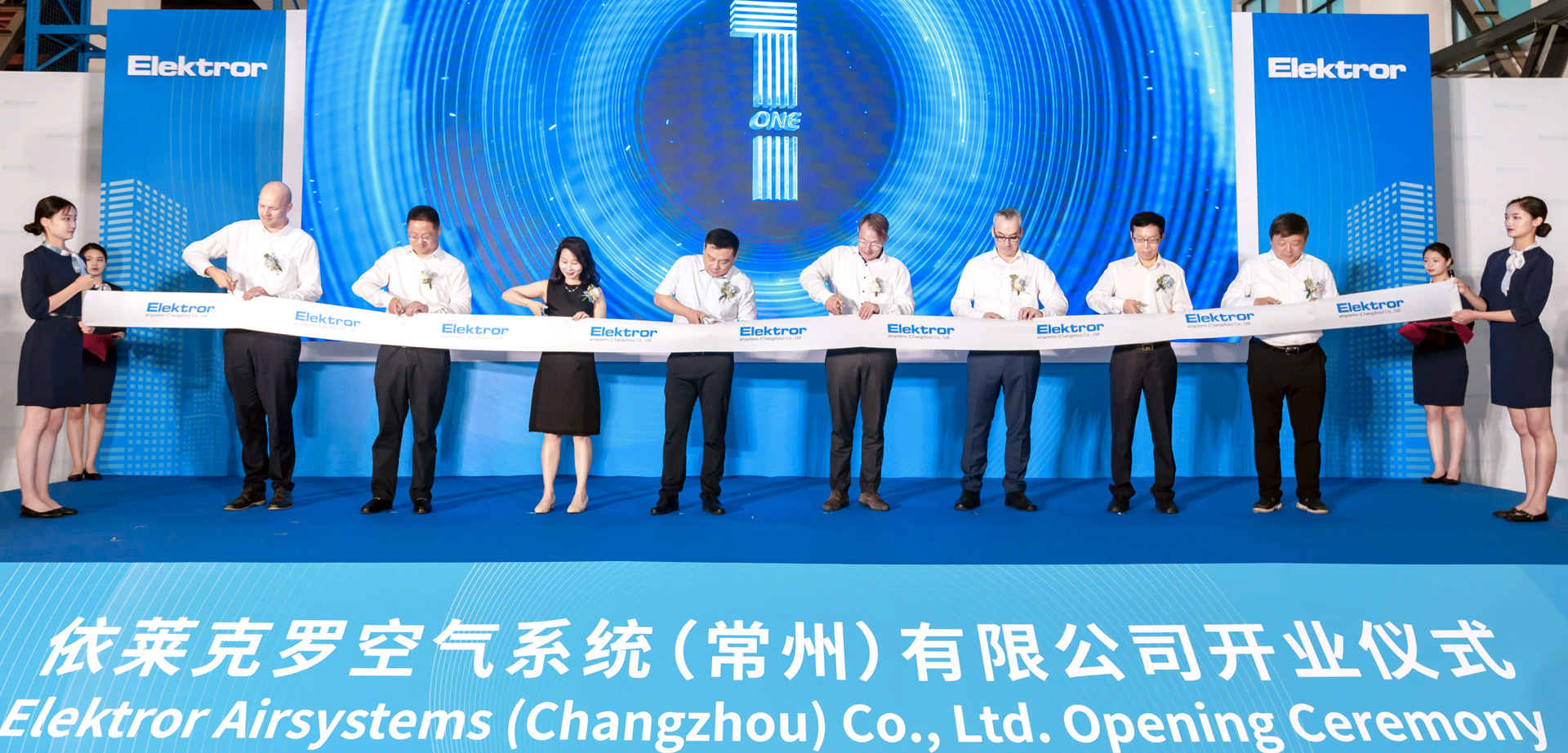 Offizielle Vertreter von Elektror und der chinesischen regierung durchschneiden ein Band vor einer LED-Wand bei der Eröffunung des neuen Elektror-Werkes in Changzhou.
