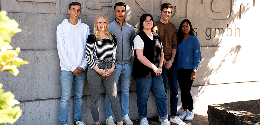 Sechs Elektrorazubis stehen vor einer Wand